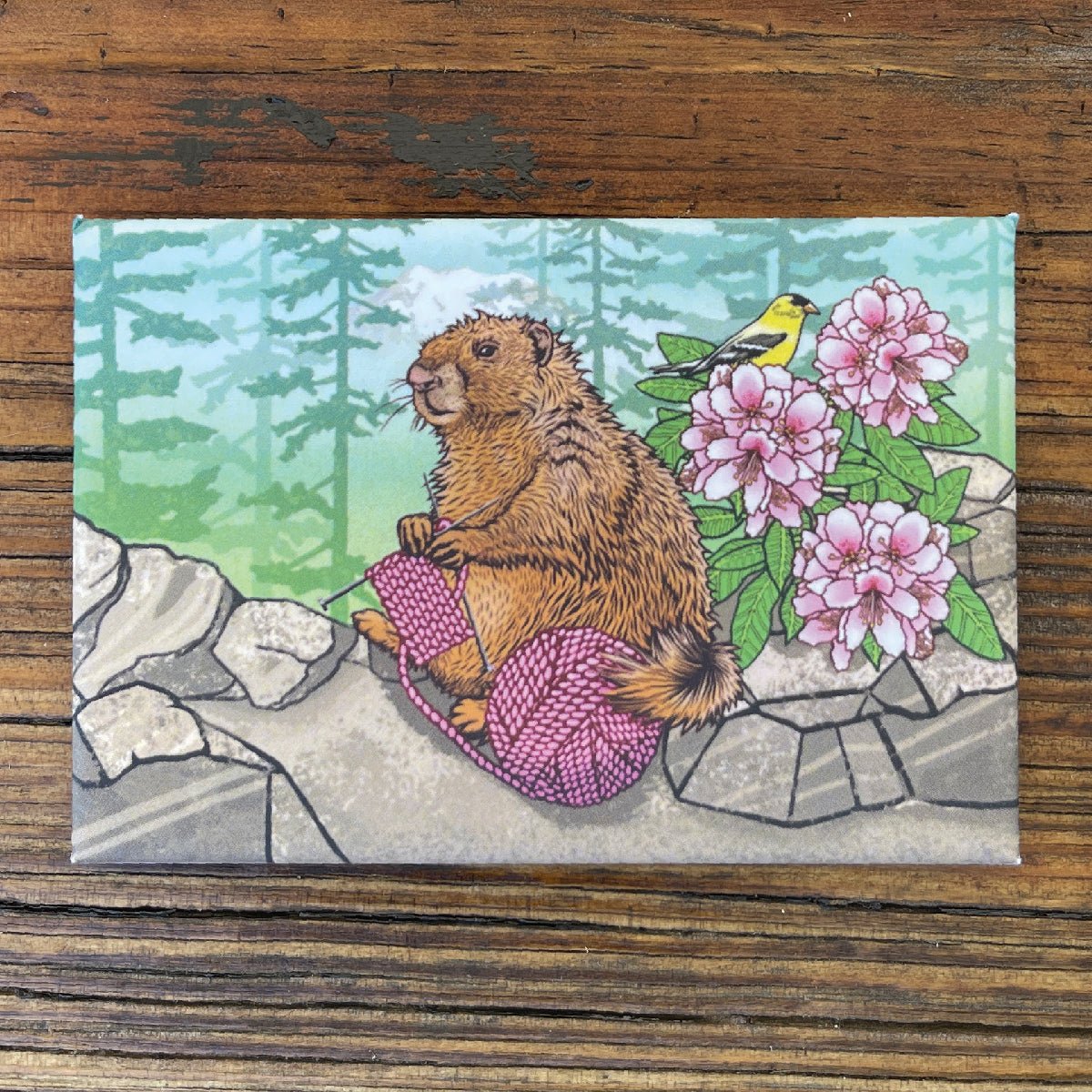 Cheerful Knitting Marmot Magnet featuring a playful marmot surrounded by pink flowers and greenery, perfect for holding important notes on your fridge!