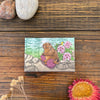 Lovely Knitting Marmot Magnet with a cute marmot and blooming flowers, placed on rustic wooden textures, making it a charming decorative accessory for any kitchen or office!