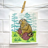 Knitting Marmot Swedish Dishcloth displayed hanging on a line, showcasing the playful design of a knitting marmot in a natural setting.
