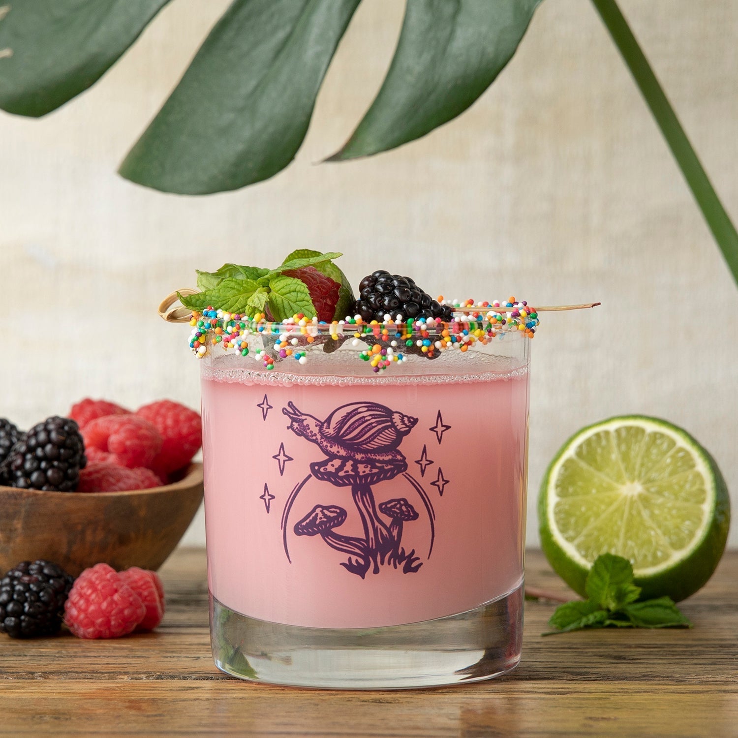 Mix and Match Your Own 6 Unique Whiskey Glass Set with a vibrant pink cocktail adorned with a charming illustrated snail and colorful sprinkles.