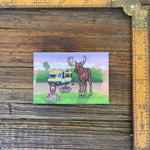 Moose In Boots Fridge Magnet next to a ruler, showcasing its charming design with a moose by a camper, ideal for moose themed decor.