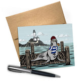 Sailor Sea Lion Blank Greeting Card with A2 Envelope featuring a whimsical sea lion in a sailor outfit standing on a dock with a lighthouse in the background, perfect for nautical themed occasions.
