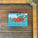 Charming octopus fridge magnet illustrated with a red octopus surrounded by ocean waves, measuring 2" x 3" for a delightful kitchen accessory.