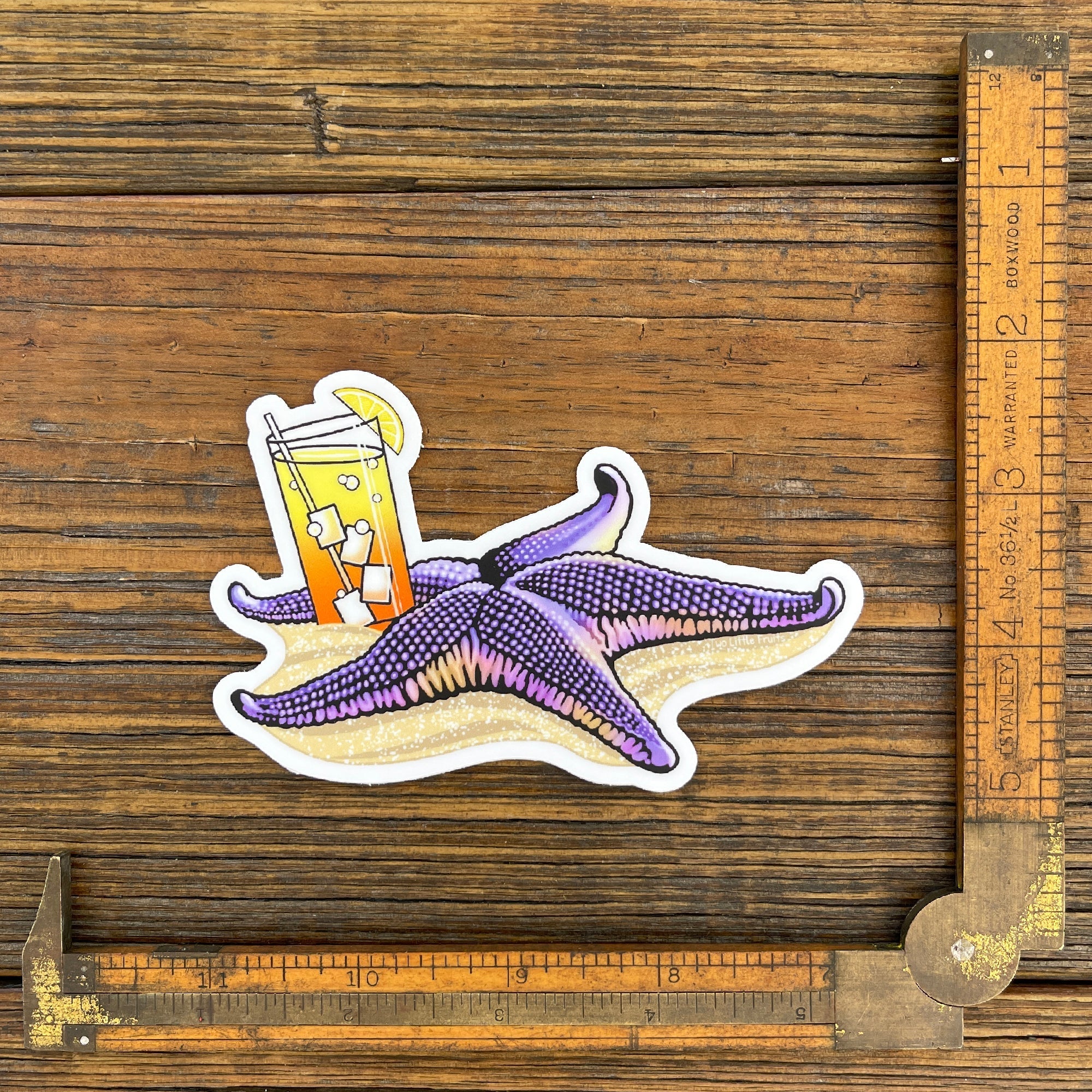 Tipsy Starfish Sticker displayed next to a ruler, showcasing its size and vibrant design of a starfish and cocktail on sandy beach.